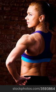 strong woman is posing against brick wall