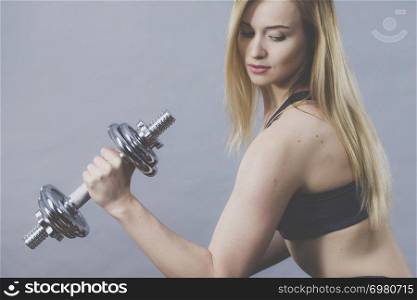 Strong woman lifting dumbbells weights. Fit girl attractive blonde model exercising gaining building muscles. Fitness and bodybuilding, on grey. Fit woman lifting dumbbells weights