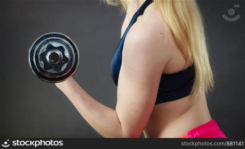 Strong woman lifting dumbbells weights. Fit girl attractive blonde model exercising gaining building muscles. Fitness and bodybuilding. Side view on dark gray. Fit woman lifting dumbbells weights