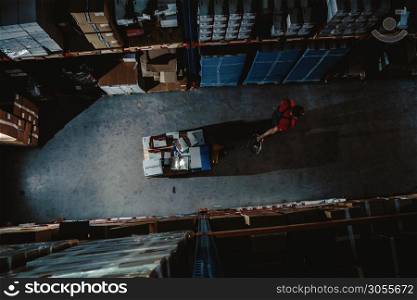 Strong worker on big warehouse. Lot of boxes at dark interior and top aerial view