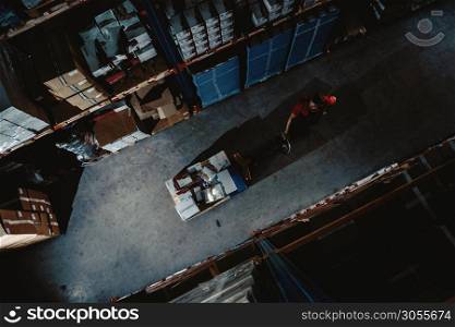 Strong worker on big warehouse. Lot of boxes at dark interior and top aerial view