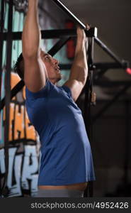 strong young man doing pull ups on a bar in a gym