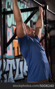 strong young man doing pull ups on a bar in a gym