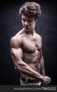 Strong young man looked down dissatisfied to his arm muscles