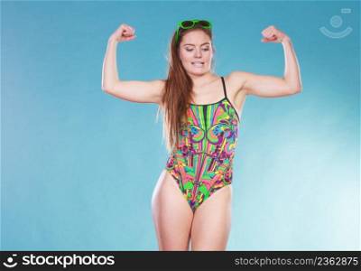 Strong young woman girl in swimsuit swimwear with sunglasses showing off muscles on blue. Summer holiday vacation relax.. Strong woman girl in swimsuit showing off muscles.