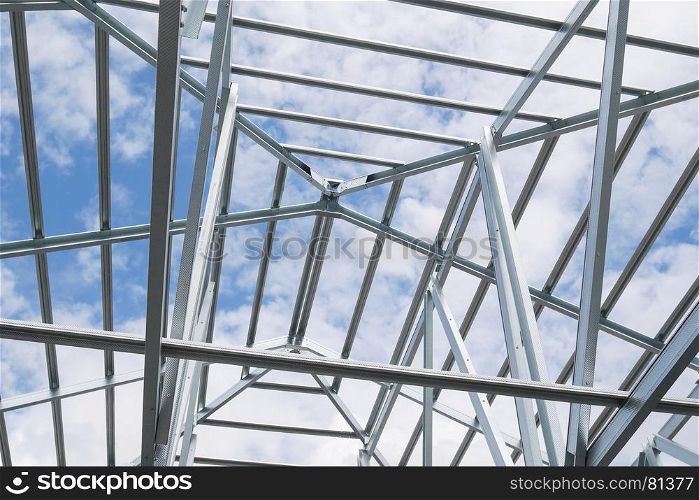 Structure of steel roof frame with blue sky and clouds at construction site