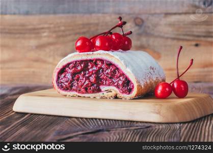 Strudel with cherry filling on wooden background