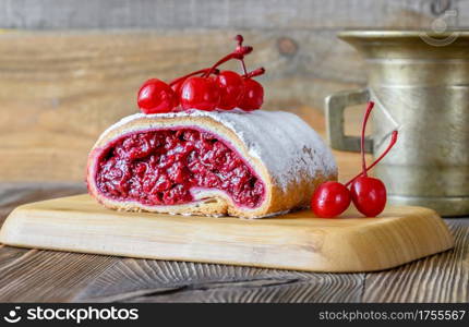 Strudel with cherry filling on wooden background