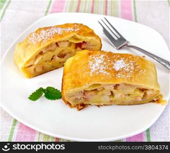Strudel with pears in a white plate with a fork on a linen tablecloth background