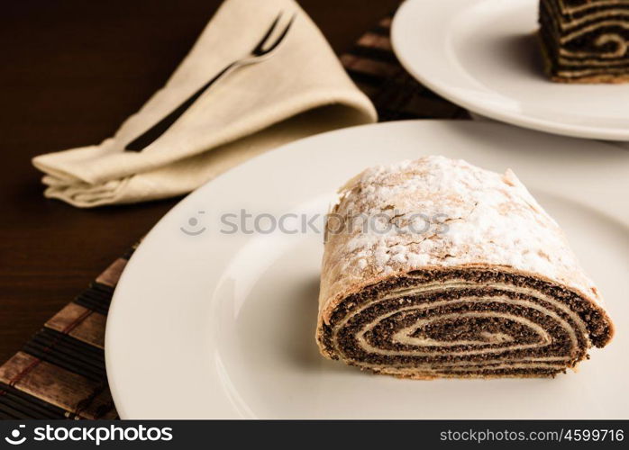 strudel with poppy seeds on a ceramic white plate on wooden background