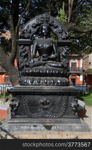 Ststue of black Buddha in in inner yard of residential district of Patan, Nepal