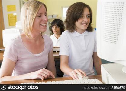 Student and teacher at computer terminal with student in background