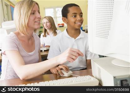 Student and teacher at computer terminal with student in background