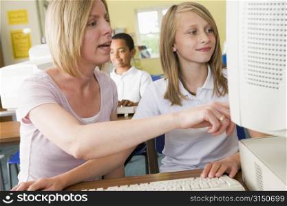 Student and teacher at computer terminal with student in background (selective focus)