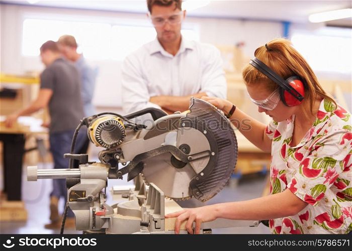 Student And Teacher In Carpentry Class Using Circular Saw