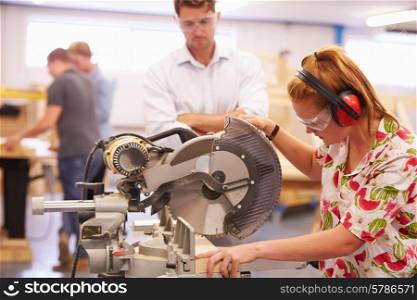 Student And Teacher In Carpentry Class Using Circular Saw