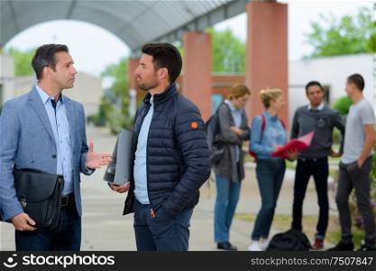 student and teacher talking outside the university
