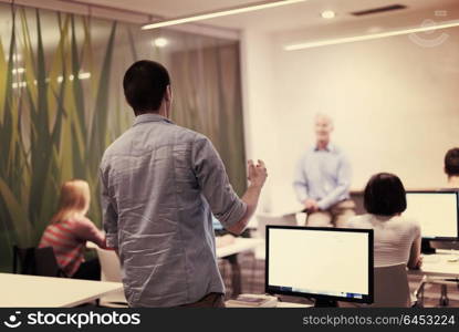 student answering a question in classroom, mature teacher and students in computer lab classroom