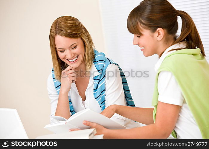 Student at home - two woman with book and laptop study together