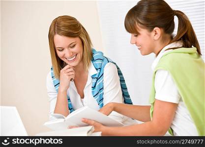 Student at home - two woman with book and laptop study together