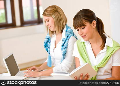 Student at home - two woman with book and laptop study together