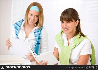 Student at home - two young woman study together with book