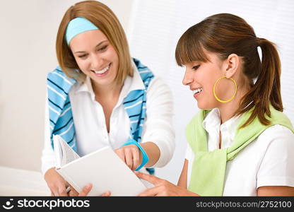 Student at home - two young woman study together with book