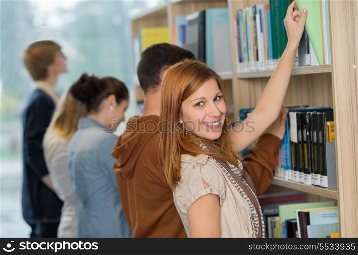 Student choosing book from bookshelf with friend in college library