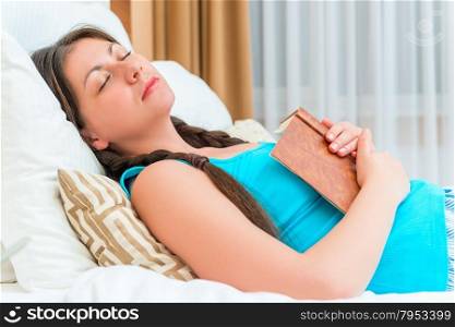 student fell asleep on the bed with a book in hand