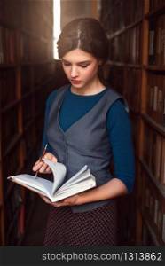 Student girl choose book with pen and notebook in her hands. Vintage library on the background.. Girl choose book with notebook in her hands.