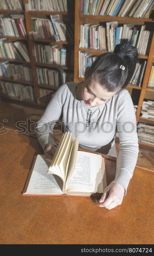 Student girl in a library. Looking at book