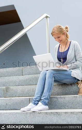 Student girl on stairs with laptop computer smiling outdoor