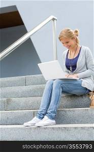 Student girl on stairs with laptop computer smiling outdoor