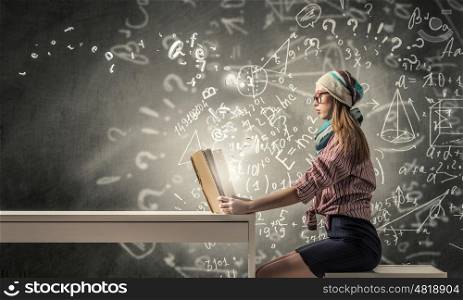 Student girl read book. Hipster girl in glasses sitting at table and reading book