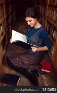 Student girl with open book reading it in university library.. Student girl with open book in university library.