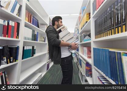 Student holding lot of books in school library. Hard worker and persistence concept.