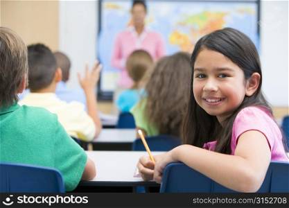 Student in class looking at camera with teacher in background (selective focus)
