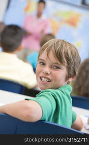 Student in class looking at camera with teacher in background (selective focus)