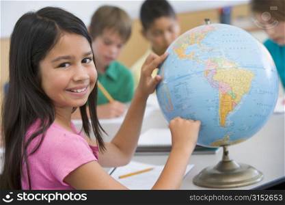 Student in class pointing at a globe (selective focus)