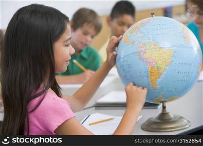 Student in class pointing at a globe (selective focus)