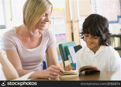 Student in class reading book with teacher