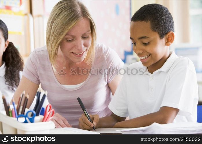 Student in class taking notes with teacher helping
