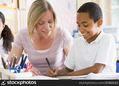 Student in class taking notes with teacher helping