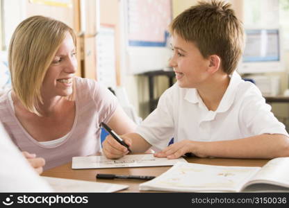 Student in class taking notes with teacher helping