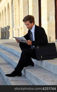 Student in law reading newspaper on stairs