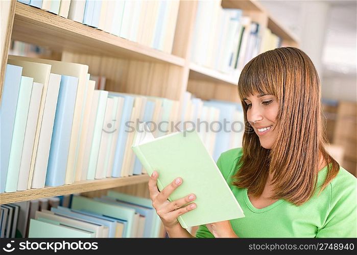 Student in library - happy woman read book at bookshelf