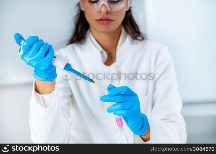 Student in White Coat, Working in Research Laboratory Using Micro Pipette and Test Tube