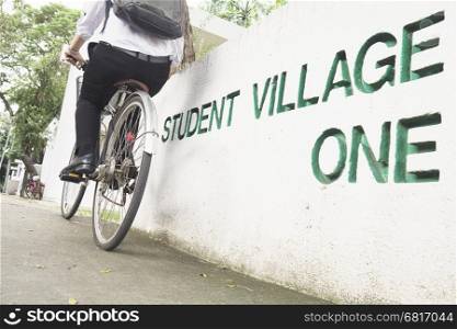 Student is riding bicycle in village green campus