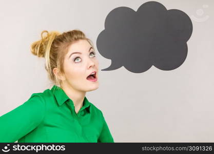 Student looking business woman wearing green shirt talking, black thinking bubble on grey background.. Woman holding black thinking bubble