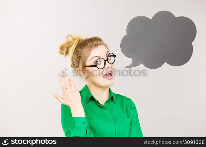 Student looking business woman wearing green shirt talking, black thinking bubble on grey background.. Woman holding black thinking bubble